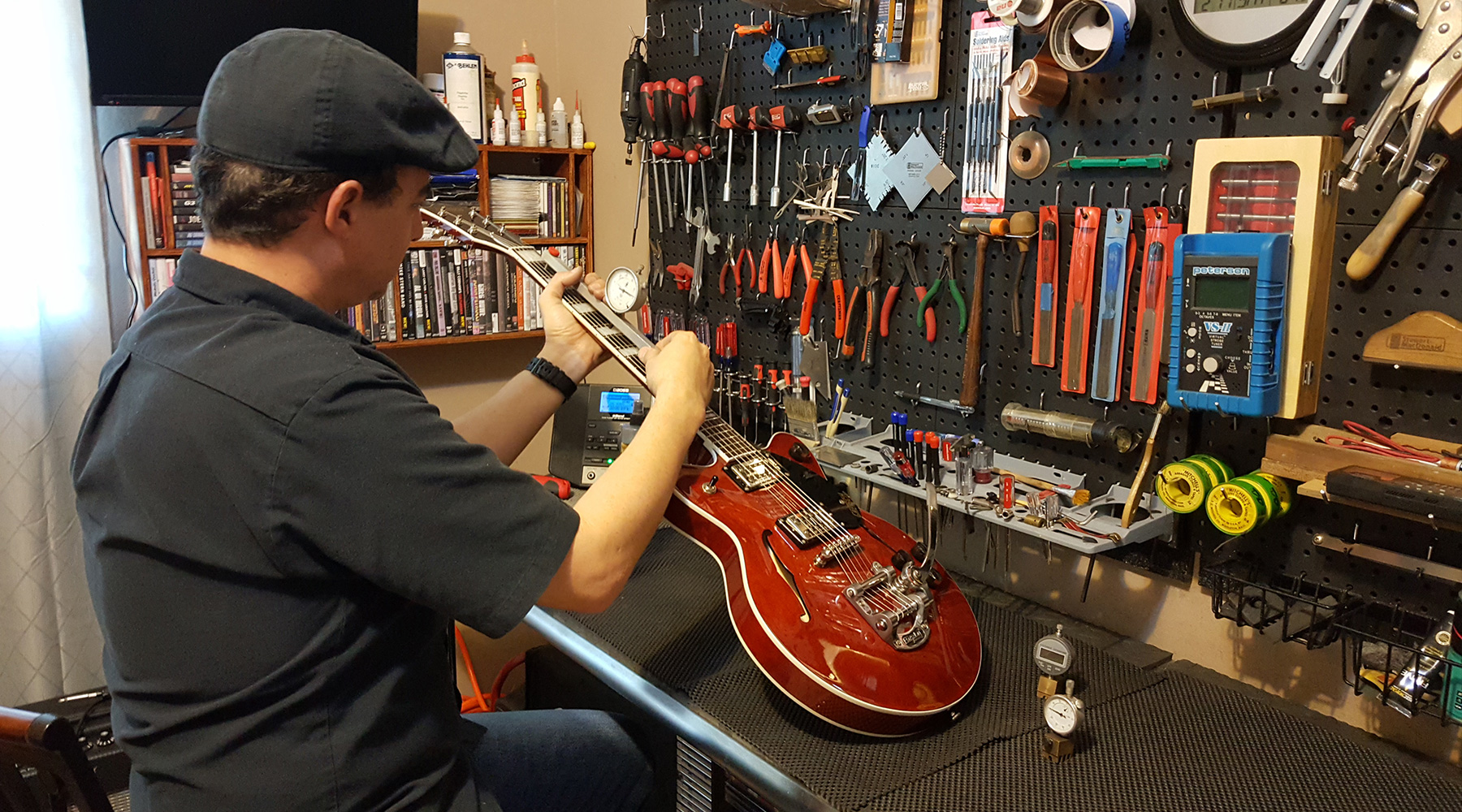 Joseph Robles trabajando una guitarra roja en el banco de JRH Guitar Repair
